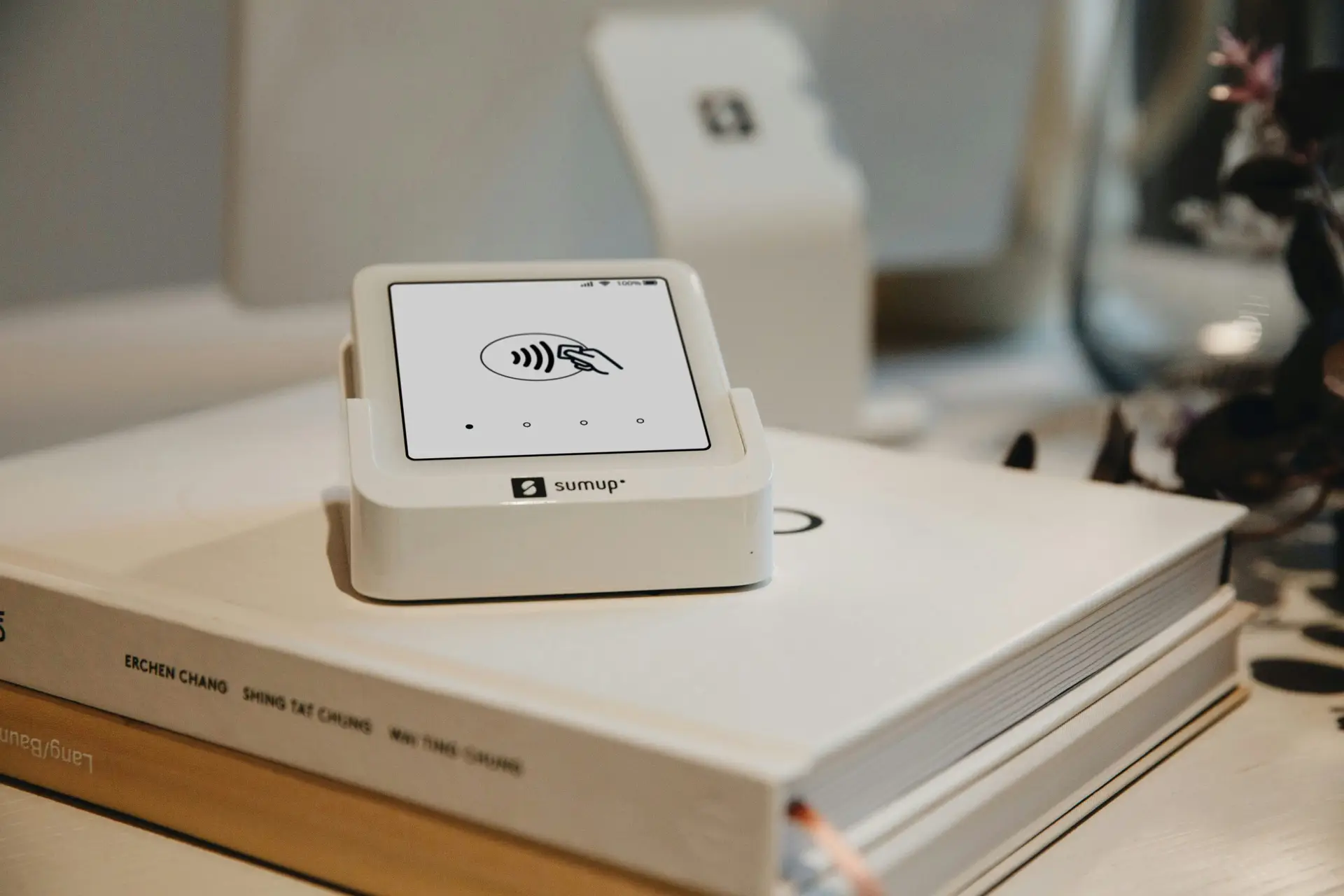 Close-up of the SumUp Solo card reader resting on a book in a warm, minimal retail setup. A modern and clean environment that highlights the elegance of digital payment tools for small businesses.