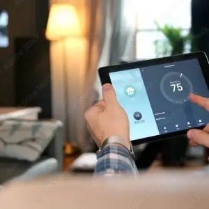Man is Adjusting a temperature using a tablet with smart home app in modern living room